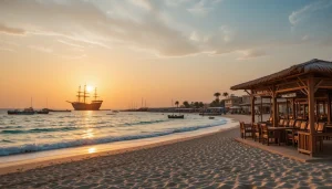 جاهای دیدنی کیش،غروب ساحل مرجان کیش با آب‌های فیروزه‌ای و کشتی یونانی در دوردست، زیر نور نارنجی و صورتی آسمان.