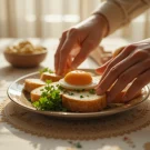 "دست در حال چیدن سریع سفره افطاری با نون و پنیر، تخم‌مرغ آب‌پز، سبزی و خرما برای جواب به افطاری چی درست کنم در روزهای شلوغ